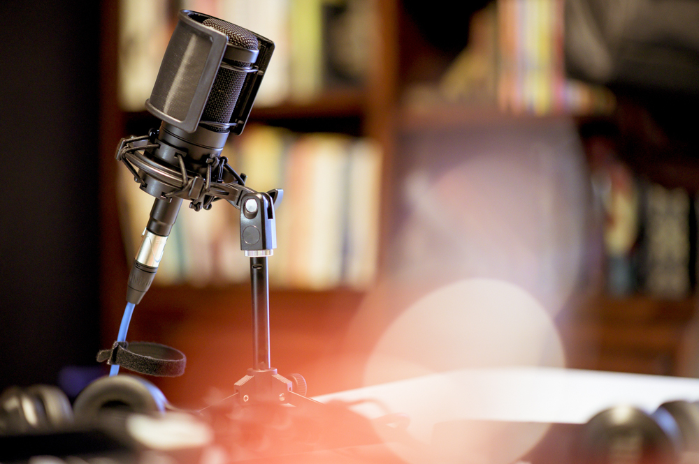 A microphone in a studio surrounded by equipment under the lights with a blurry background